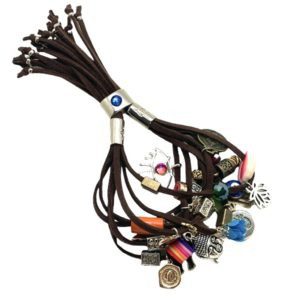 Pulsera de Gamuza con dijes de diferentes metales, flecos, muñequitas y flores café